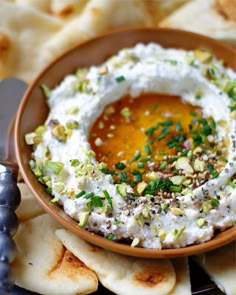 a bowl filled with hummus and sauce on top of pita chips