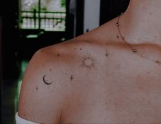 the back of a woman's shoulder with stars and a sun tattoo on it