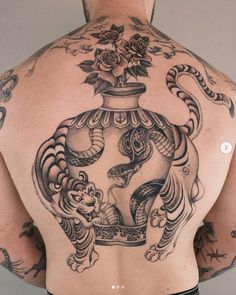 the back of a man with tattoos on his body and chest, holding an ornate vase