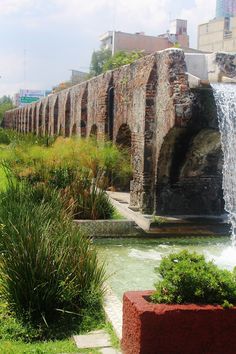 a stone bridge over a river next to a lush green field