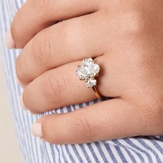 a woman's hand with a diamond ring on her left hand and a striped shirt on the right