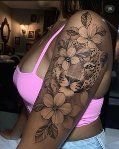 a woman's arm with flowers and a leopard tattoo on her left shoulder,