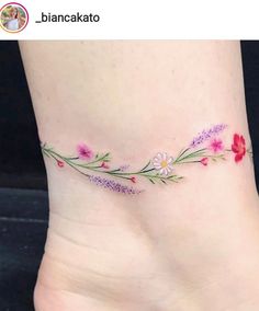 a woman's foot with flowers and leaves on the bottom part of her ankle