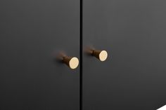 two black cabinets with brass handles and knobs on the doors, side by side