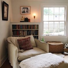 a living room filled with furniture and a book shelf next to a window covered in books