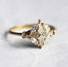 a three stone diamond ring sitting on top of a white surface with gold trimmings