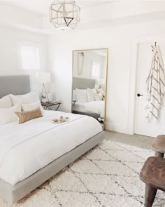 a bedroom with a large bed, mirror and chair in it's centerpiece