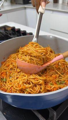 someone is stirring spaghetti in a pan on the stove