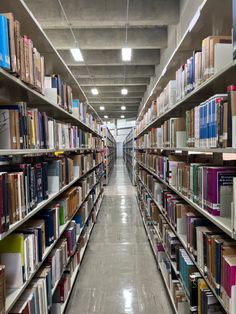 a long row of books on shelves in a large room with light coming through the ceiling