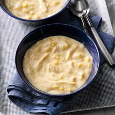 two bowls filled with soup on top of a blue cloth next to silver spoons