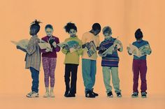 five children standing in a row with books and papers on their hands, all looking at the same direction