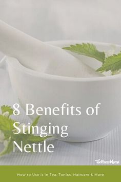 a white bowl filled with green leaves next to a spoon