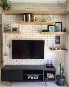 there is a television on the wall in the living room with bookshelves and plants