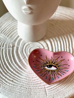 a pink heart shaped bowl with an eye on it