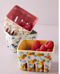 three ceramic containers with raspberries in them