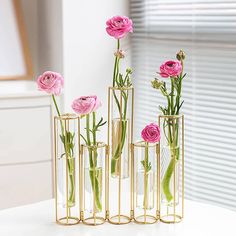 three vases with pink flowers in them on a white table next to a window