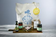 an assortment of condiments are displayed on a wooden cutting board with a white tote bag