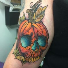 a person with a tattoo on their arm and an orange skull in the middle of it