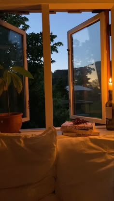 a living room with two large windows and a candle on the table in front of it