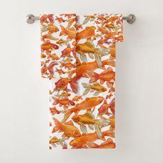 an orange and white towel with goldfish on it, hanging from a metal bar