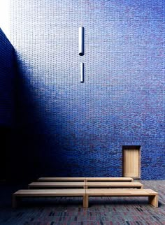 a wooden bench sitting in front of a blue wall