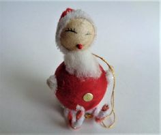 a red and white stuffed animal sitting on top of a white table next to a string