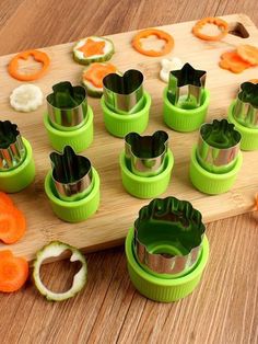 a wooden cutting board topped with green and orange vegetable cutters