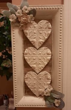 two hearts are hanging on the wall with flowers