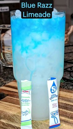 blue razz limeade in a glass with two tubes next to it on a cutting board