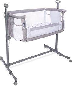 a baby crib that is sitting on top of a metal frame and has wheels