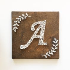 a wooden sign with the letter a on it's side and leaves around it