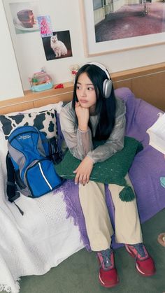 a woman sitting on top of a bed wearing headphones