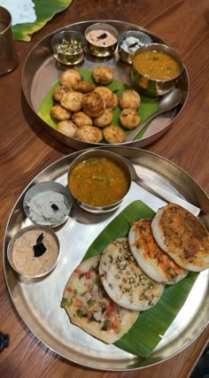 two metal plates with food on them sitting on a table