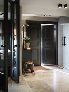 an open door leading into a room with two stools and plants on the floor