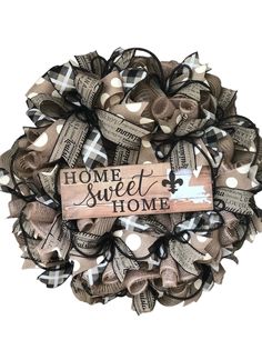 a wreath with the words home sweet and some bows hanging from it's side