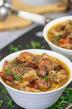 two white bowls filled with food sitting on top of a black table next to silverware