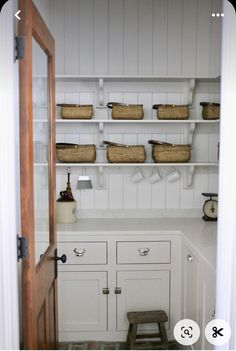 a kitchen with white cabinets and baskets on the shelves