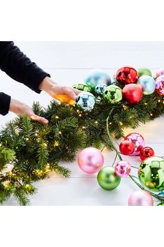 someone decorating a christmas garland with ornaments