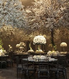 the tables and chairs are set up with white flowers on them, along with tall centerpieces