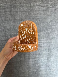 a hand holding a piece of bread with white flowers painted on the inside of it