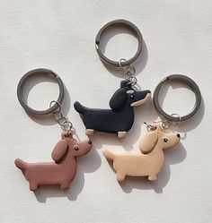 four keychains shaped like dogs sitting on top of a white surface with one dog in the middle