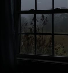 an open window in a dark room with fog coming through the windows and trees outside