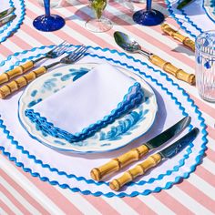 a table set with blue and white plates, silverware and napkins on it