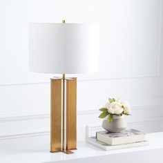 a white flower sitting on top of a table next to a lamp and bookend