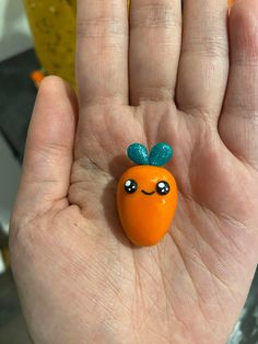 a hand holding an orange with a green bow on it's head and eyes