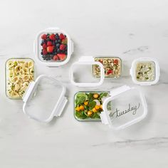 six plastic containers filled with food on top of a white countertop next to each other