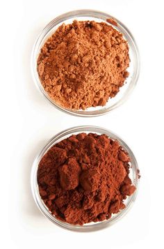 two bowls filled with different colored powders on top of a white table next to each other