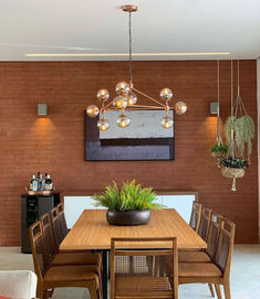 a dining room table with chairs and a potted plant on top of it in front of a brick wall