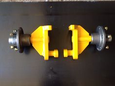 two yellow and black handles are attached to a metal surface with screws on it