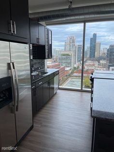 a kitchen with stainless steel appliances next to a large window overlooking the cityscape